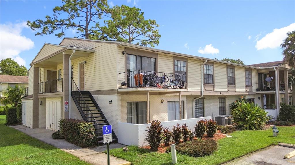 A two-story apartment building with yellow siding, a metal staircase, and a second-floor balcony — 5977 VILLAGE CIRCLE SOUTH UNIT GE, ORLANDO, FL