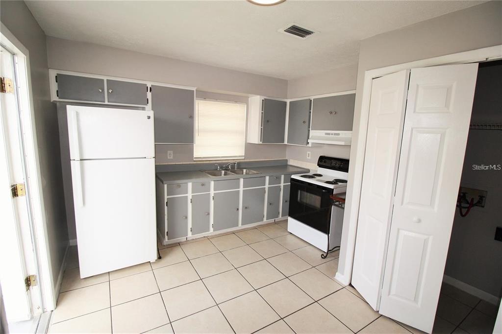 A kitchen with grey cabinets, white appliances, and light-colored tile flooring — 9418 N 50TH STREET UNIT B, TAMPA, FL