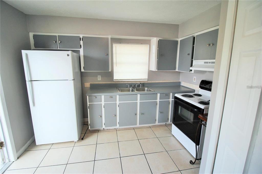 A kitchen features gray cabinets, white appliances, a double sink, and light-colored floor tiles — 9418 N 50TH STREET UNIT B, TAMPA, FL