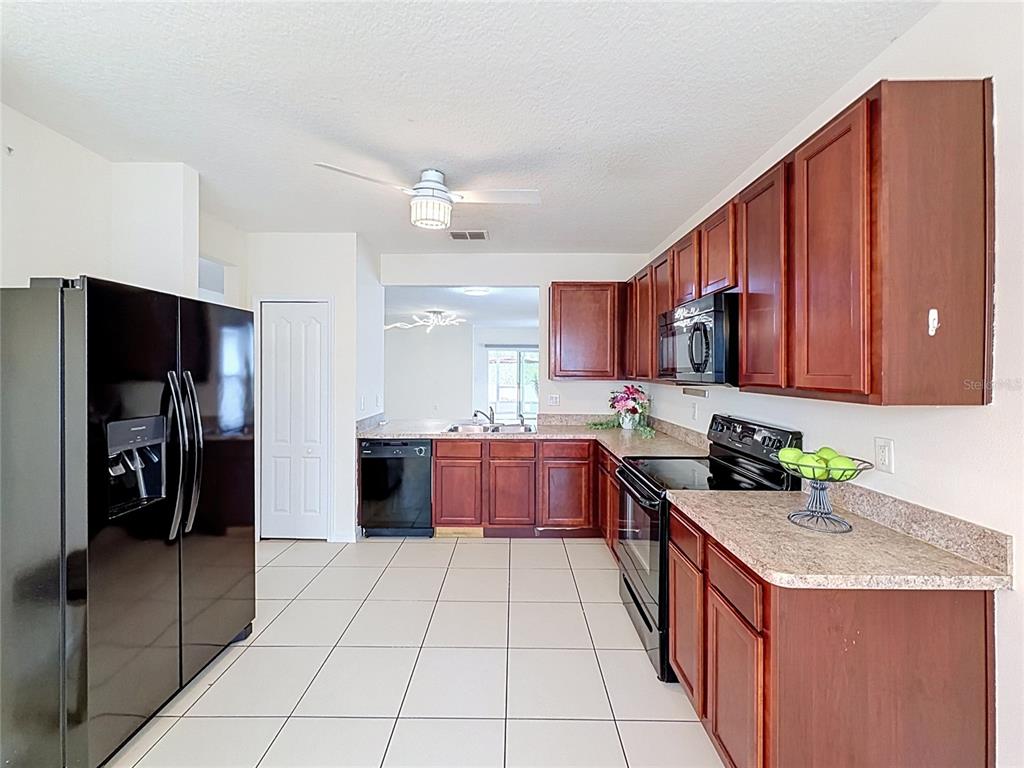 A kitchen with dark wood cabinets, black appliances, and light-colored tile flooring — 237 NOVA DRIVE, DAVENPORT, FL