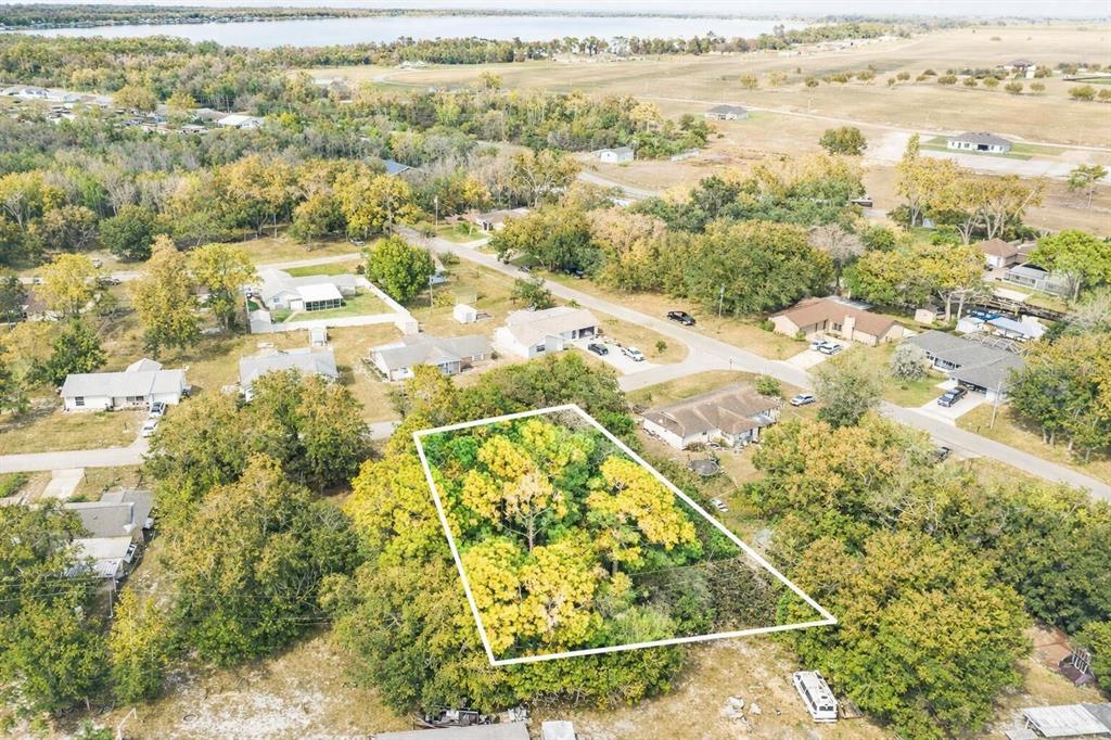 An aerial view shows a wooded, rectangular lot outlined in white within a residential neighborhood — 3044 AZALEA LANE, LAKE PLACID, FL