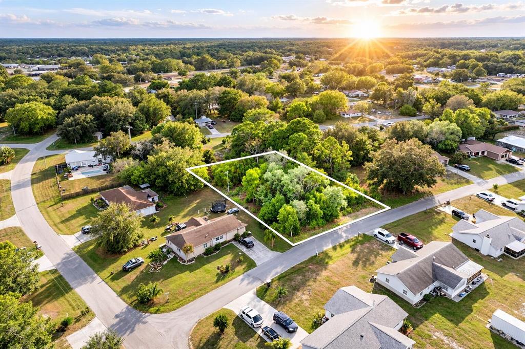An aerial view shows a vacant, tree-covered residential lot outlined in white within a neighborhood — 3044 AZALEA LANE, LAKE PLACID, FL