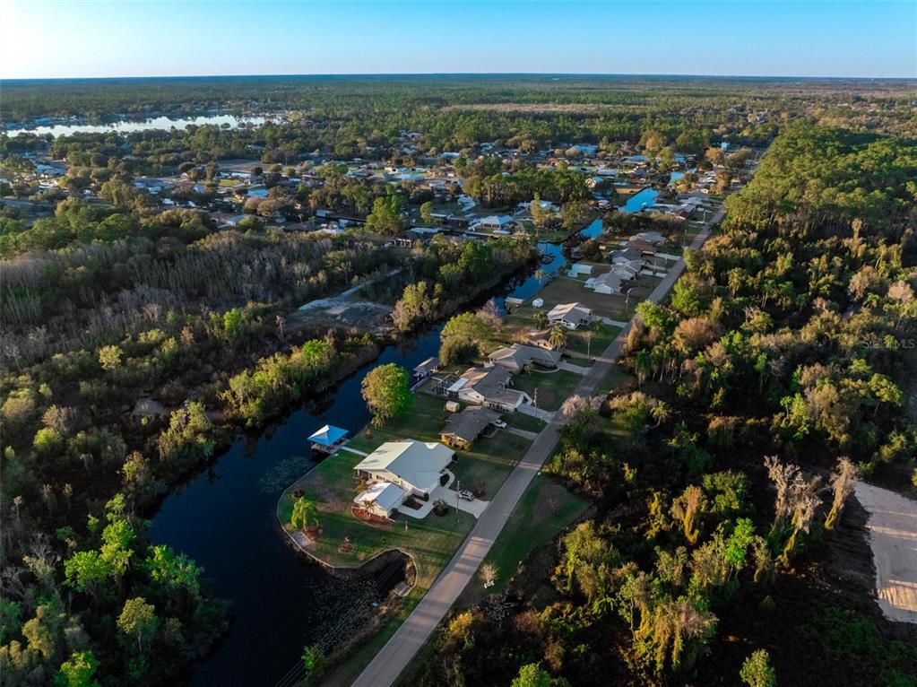 An aerial view shows houses along a canal surrounded by dense trees and vegetation — 3044 AZALEA LANE, LAKE PLACID, FL