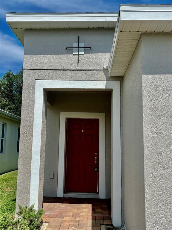 The exterior of a house features a red front door under a covered entryway — 3215 STRATTON CIRCLE, KISSIMMEE, FL