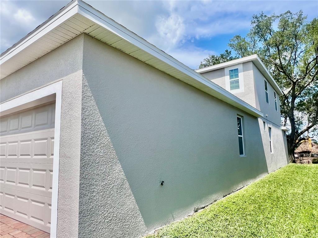 The exterior side of a two-story house features a garage, stucco walls, and windows — 3215 STRATTON CIRCLE, KISSIMMEE, FL