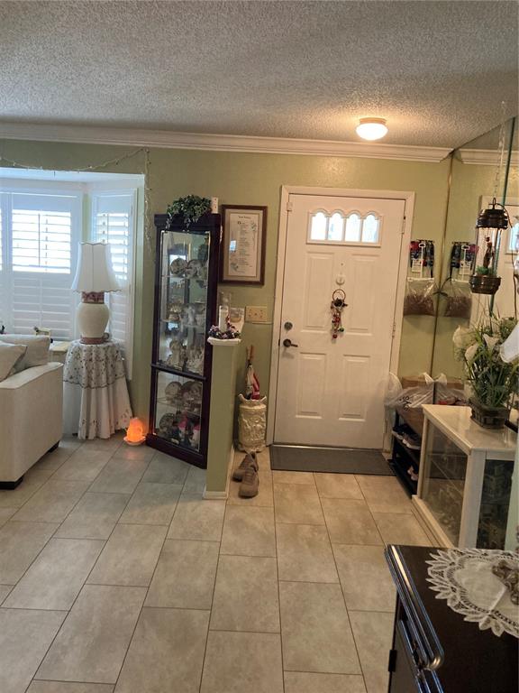 An entryway features tile flooring, a white front door, and a tall glass display cabinet — 9902 ST. JOSEPH, NEW PORT RICHEY, FL