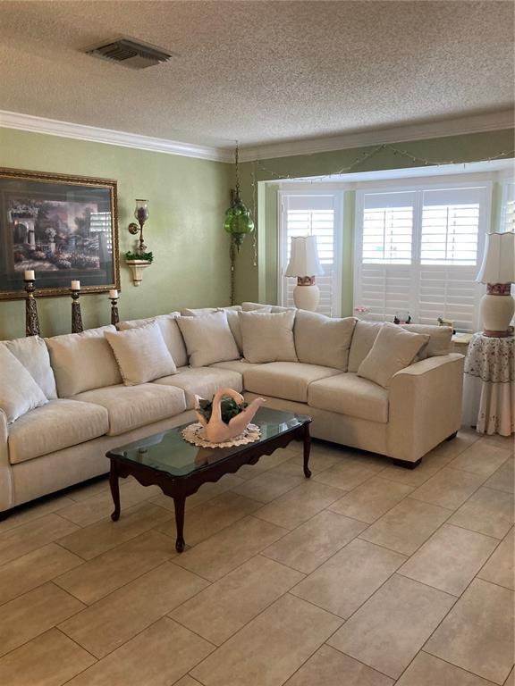 A living room features a large beige sectional sofa, a glass-top coffee table, and plantation shutters — 9902 ST. JOSEPH, NEW PORT RICHEY, FL