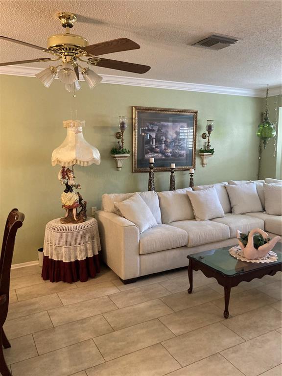 A living room features a light green wall, a beige sectional sofa, and a ceiling fan — 9902 ST. JOSEPH, NEW PORT RICHEY, FL