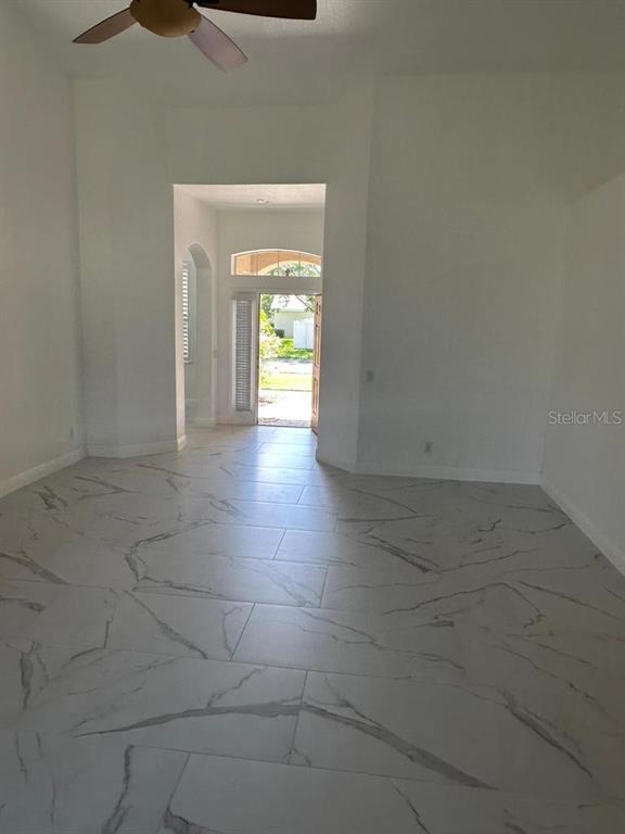 A bright room features white walls, large marble-patterned floor tiles, and a ceiling fan — 3127 CONRAD COURT, KISSIMMEE, FL
