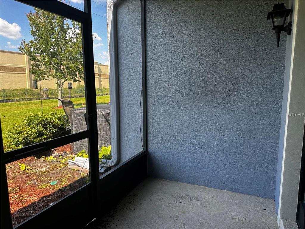 A screened-in patio with a concrete floor, blue stucco wall, and an outdoor light fixture — 1969 CHATHAM PLACE DRIVE, ORLANDO, FL