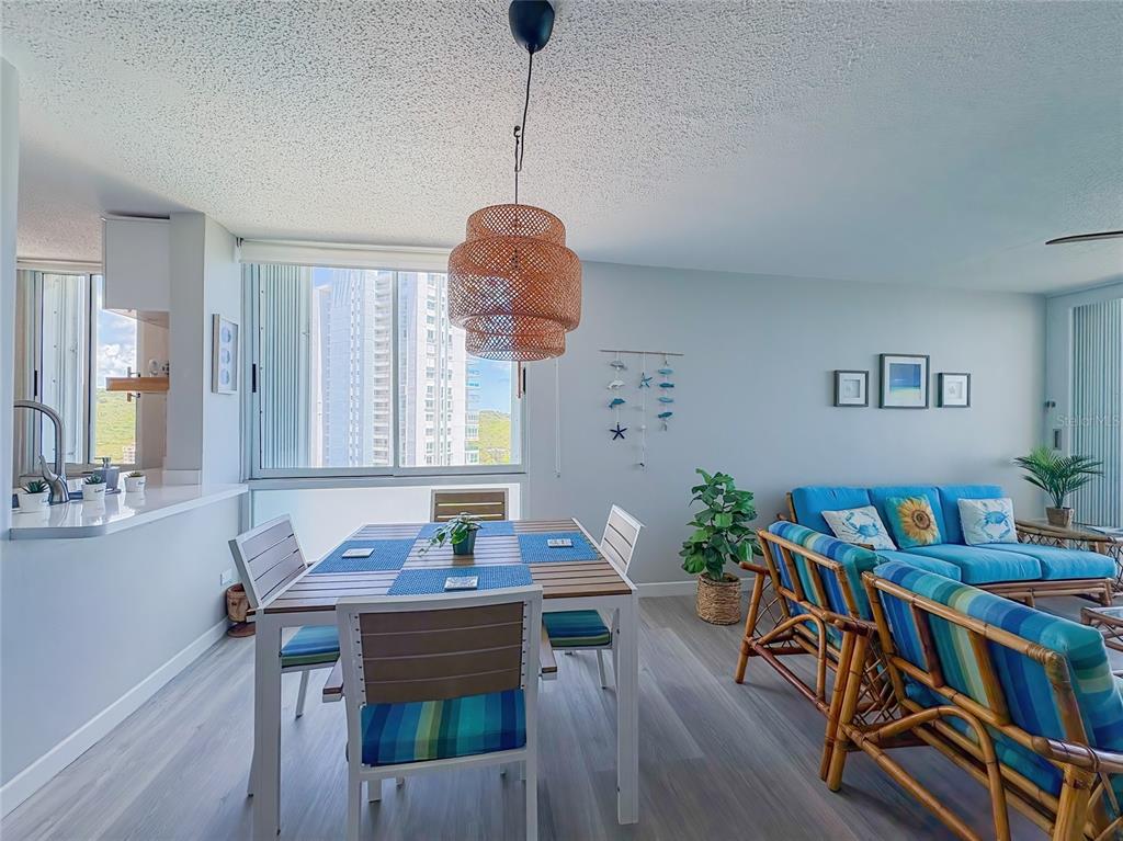A dining area with a woven pendant light sits beside a living room with blue furniture — 200 MARINA VW AVE. UNIT 1910, FAJARDO, PR