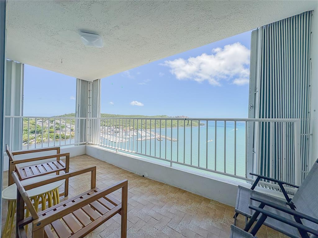 A balcony with tile flooring, metal railings, and outdoor seating overlooking a marina and ocean — 200 MARINA VW AVE. UNIT 1910, FAJARDO, PR