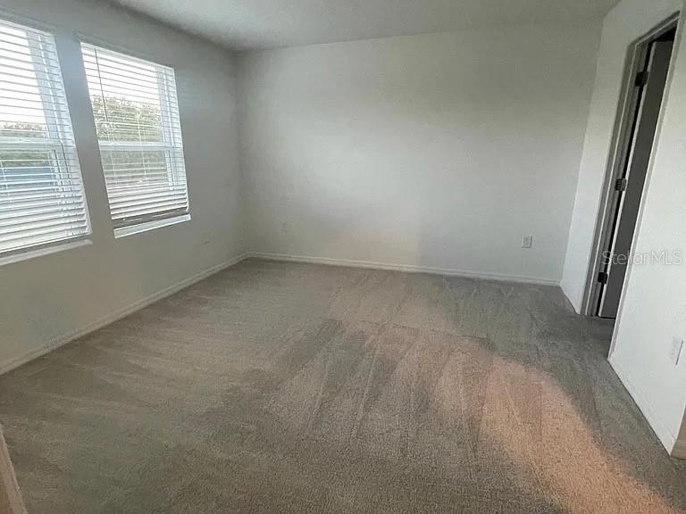 An empty bedroom features gray carpeting, white walls, and two windows with closed blinds — 3579 LANDING NET DRIVE, KISSIMMEE, FL
