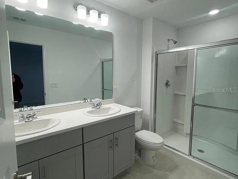 A bathroom features a double vanity with gray cabinets, a large mirror, and a shower — 3579 LANDING NET DRIVE, KISSIMMEE, FL