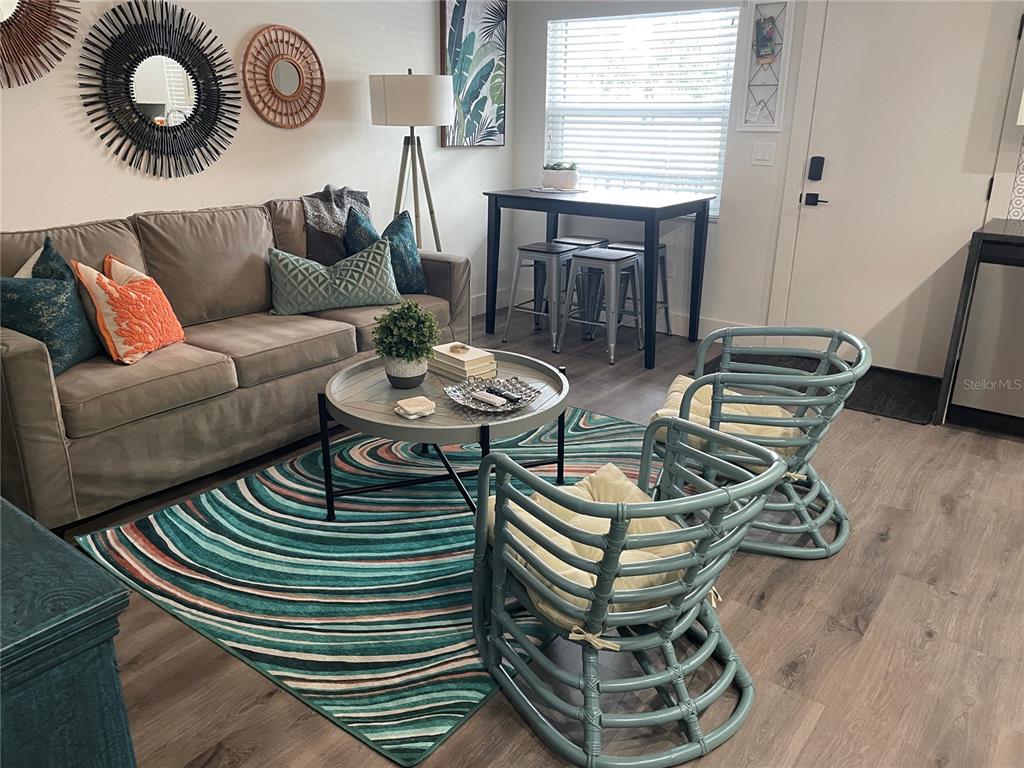 A living room features a grey sofa, two blue rattan chairs, and a patterned rug — 1910 MORRILL STREET UNIT 5, SARASOTA, FL