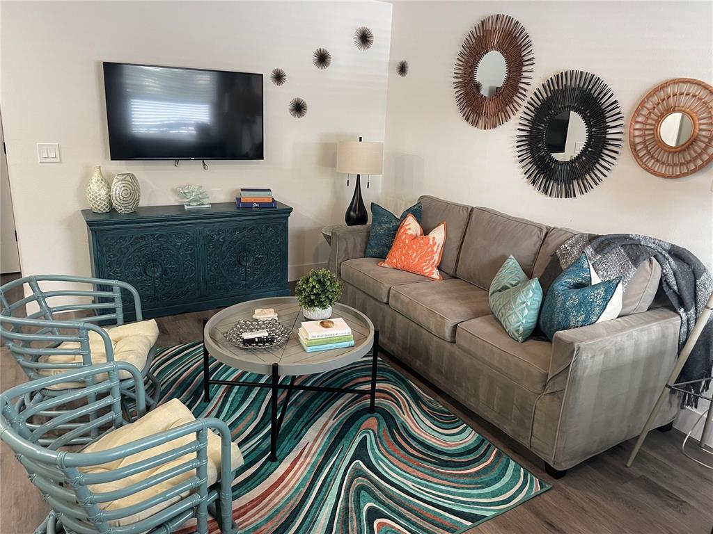A living room features a gray sofa, two blue rattan chairs, and a patterned rug — 1910 MORRILL STREET UNIT 5, SARASOTA, FL