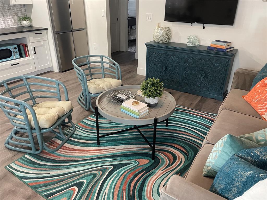 A living room features two blue rattan chairs, a round coffee table, and a patterned rug — 1910 MORRILL STREET UNIT 5, SARASOTA, FL