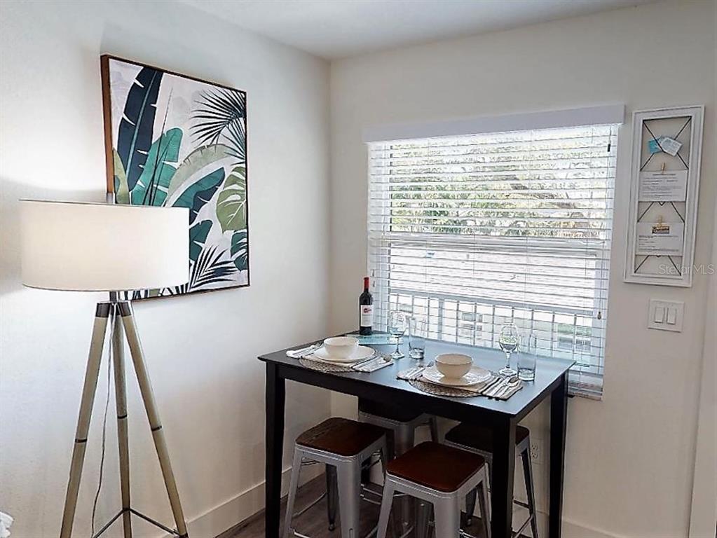 A small dining area features a dark table, two metal stools, and wall art — 1910 MORRILL STREET UNIT 5, SARASOTA, FL