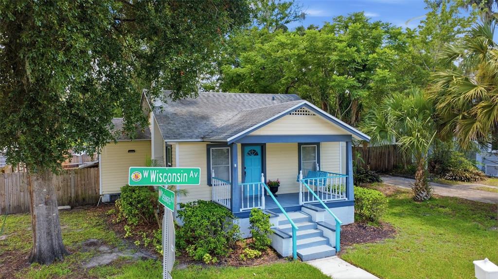 A small, light yellow bungalow with a blue front door and a covered front porch — 347 W WISCONSIN AVENUE, DELAND, FL