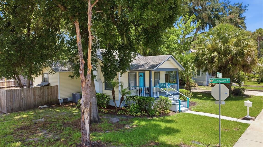 A yellow single-story house with a blue front door and a covered porch — 347 W WISCONSIN AVENUE, DELAND, FL