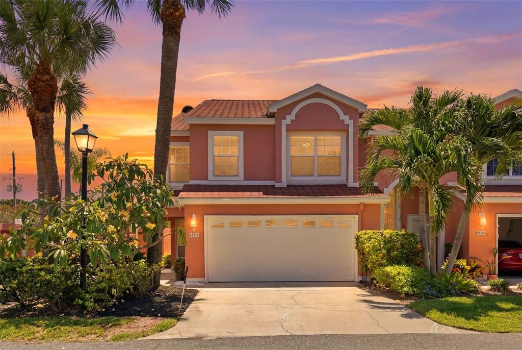 A two-story peach-colored house with a two-car garage at sunset — 14510 ALEJO COURT, SEMINOLE, FL