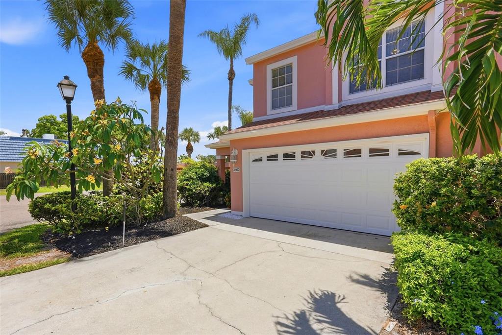A pink two-story house features a white garage door, a concrete driveway, and palm trees — 14510 ALEJO COURT, SEMINOLE, FL
