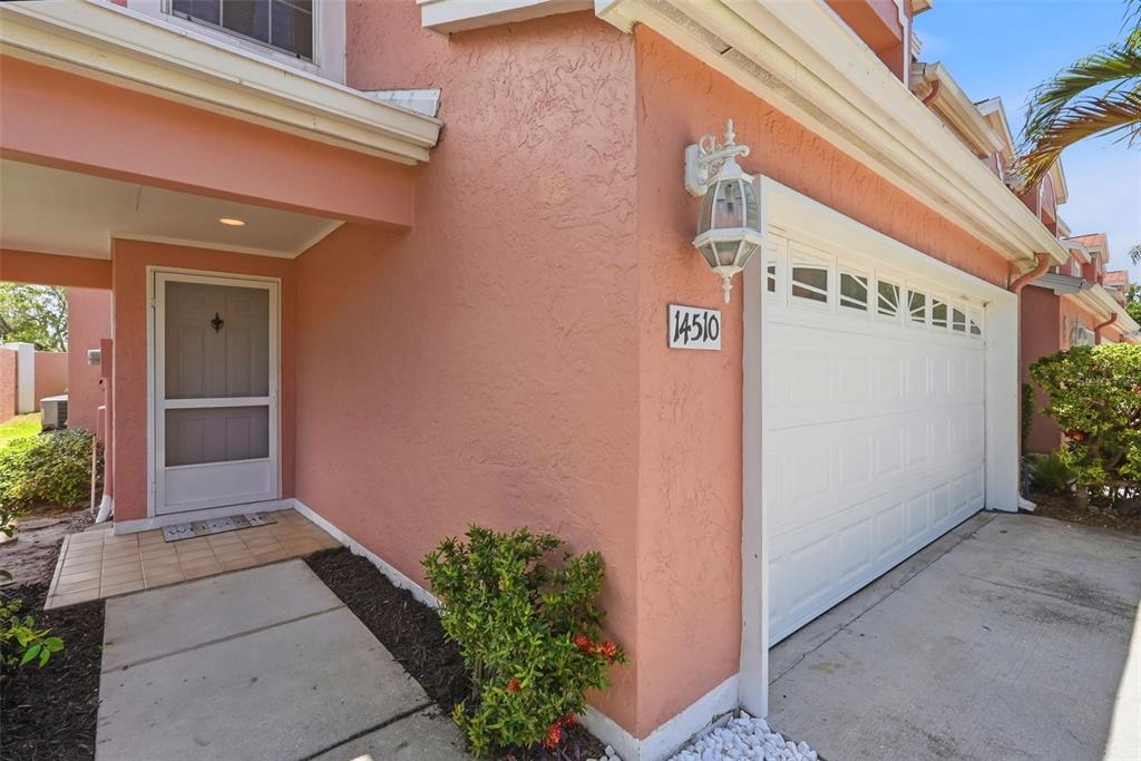 A peach-colored house exterior features a white garage door, a front entrance, and a lantern — 14510 ALEJO COURT, SEMINOLE, FL
