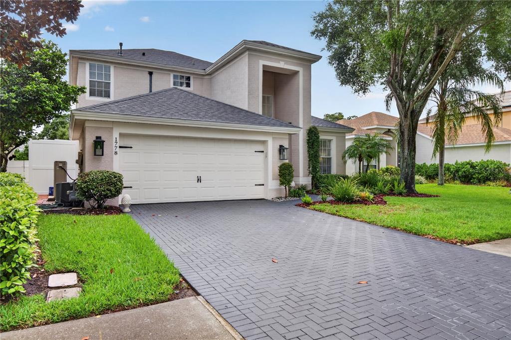 A two-story house with a white garage door and a dark gray herringbone brick driveway — 1778 BRILAND STREET, TARPON SPRINGS, FL