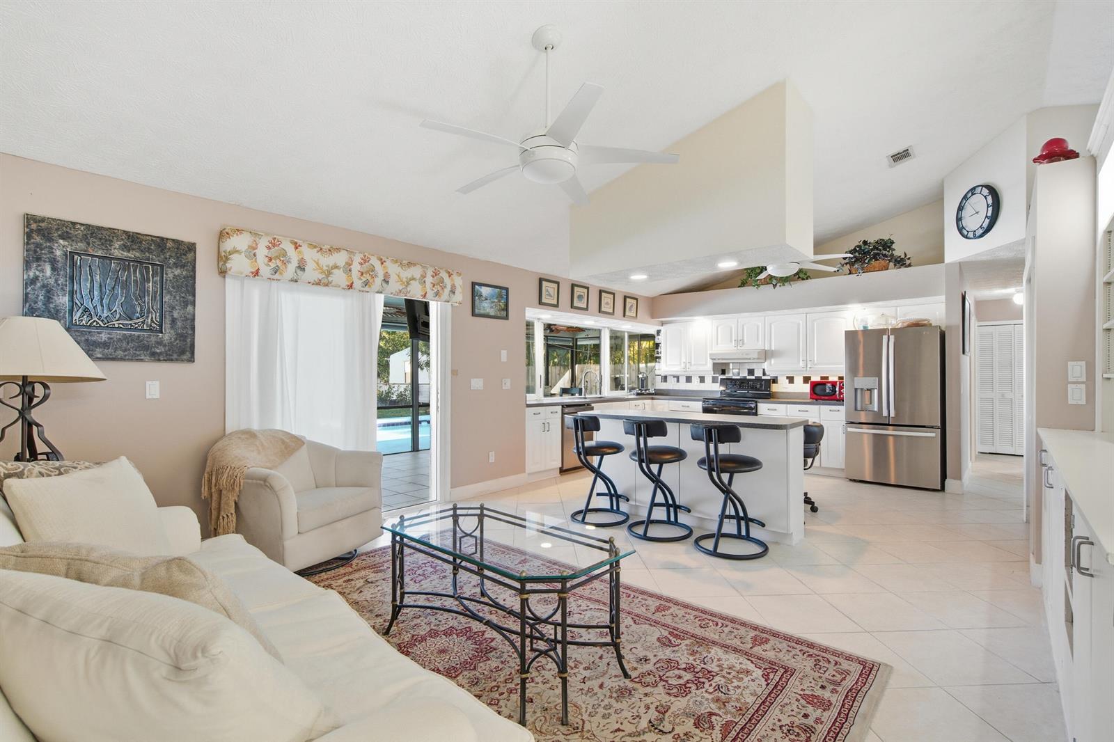 A living room and kitchen open floor plan features white cabinets, a breakfast bar, and tile — 1569 NE Amy Avenue, Jensen Beach FL 34957, JENSEN BEACH, FL