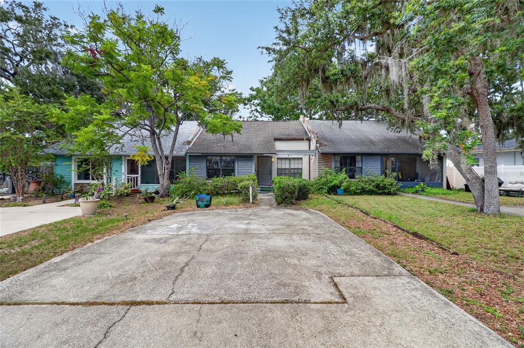 A single-story house with a concrete driveway, gray siding, and large trees in the yard — 108 12TH AVENUE S, SAFETY HARBOR, FL
