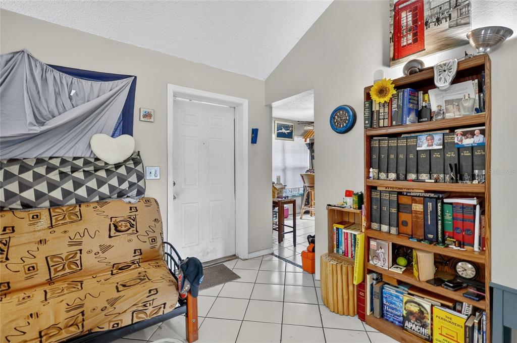 A room features a futon, a tall wooden bookshelf, and a white door — 108 12TH AVENUE S, SAFETY HARBOR, FL
