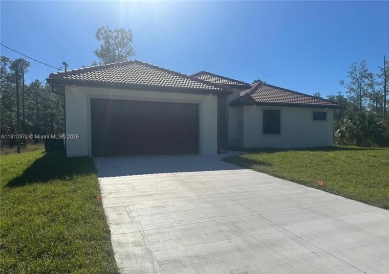 A single-story house with a tiled roof, a two-car garage, and a concrete driveway — 2002 E 13th St, Lehigh Acres FL 33972, LEHIGH ACRES, FL