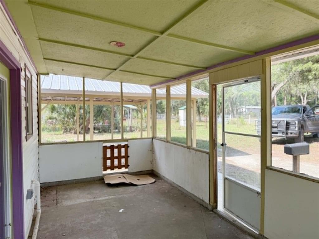 A screened-in porch with a concrete floor, white walls, and a view of a yard — 11050 NW 107TH TERRACE, CHIEFLAND, FL
