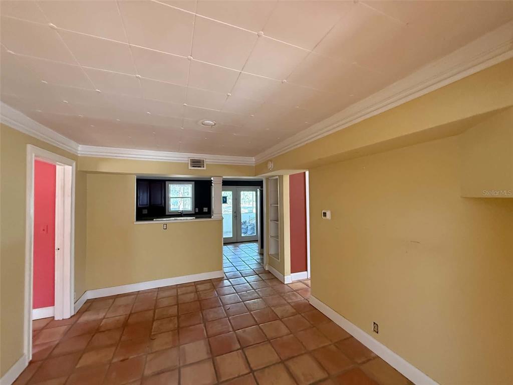 A room with yellow walls, a tiled floor, and a doorway leading to a kitchen — 11050 NW 107TH TERRACE, CHIEFLAND, FL