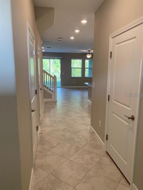 A tiled hallway leads past interior doors toward an open living area with a staircase — 18843 NOBLE CASPIAN DRIVE, LUTZ, FL