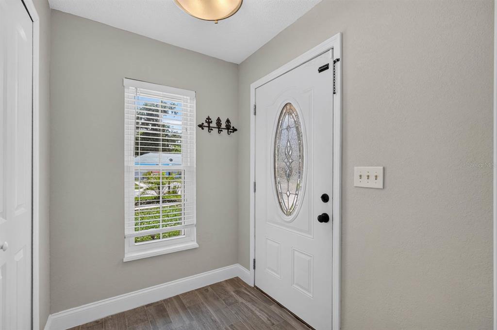 An entryway features a white front door with a glass insert, a window, and wood-look flooring — 1017 E INDIAN OAKS, DAYTONA BEACH, FL