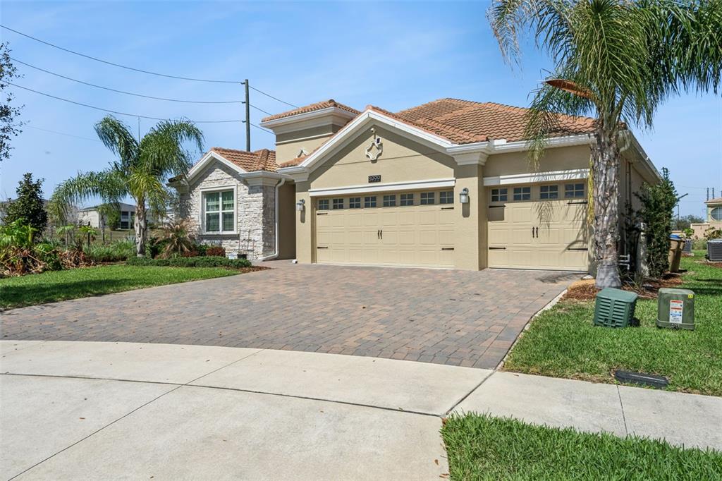 A single-story house with a stone facade, a three-car garage, and a paved driveway — 8999 CROQUET COURT, DAVENPORT, FL