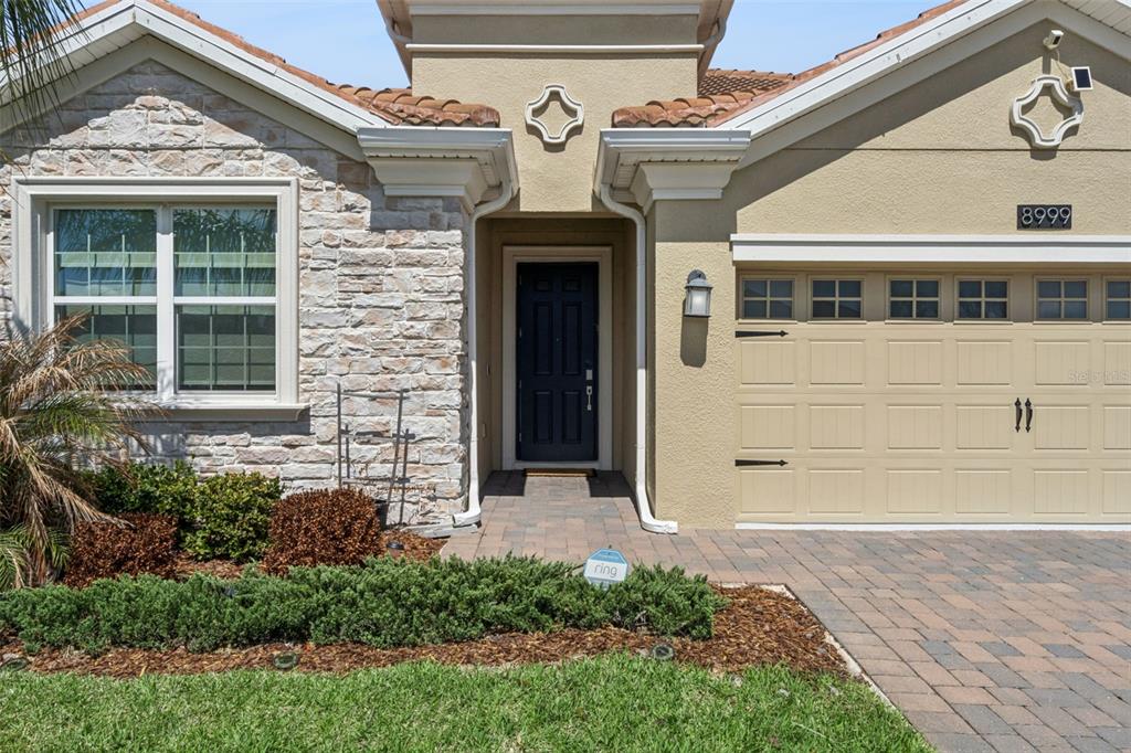The exterior of a house features a stone facade, a dark front door, and a garage — 8999 CROQUET COURT, DAVENPORT, FL