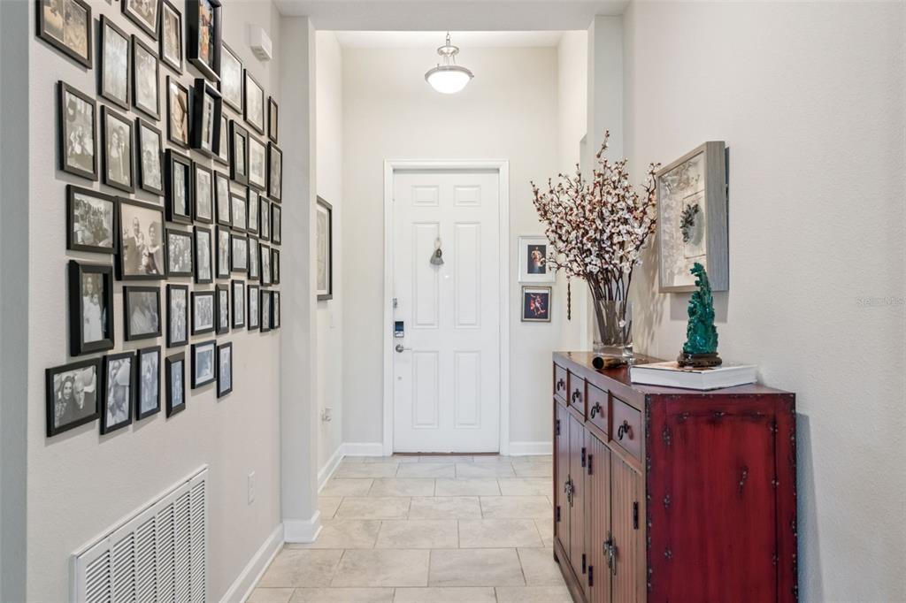 A hallway features a gallery wall of framed photos, tiled flooring, and a red cabinet — 8999 CROQUET COURT, DAVENPORT, FL