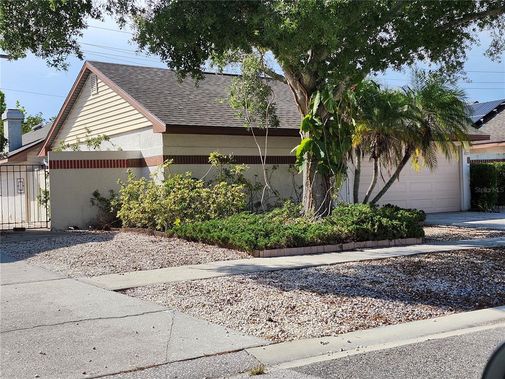 A single-story house features a tan exterior, a garage, and a landscaped front yard — 7125 SILVERMILL DRIVE, TAMPA, FL