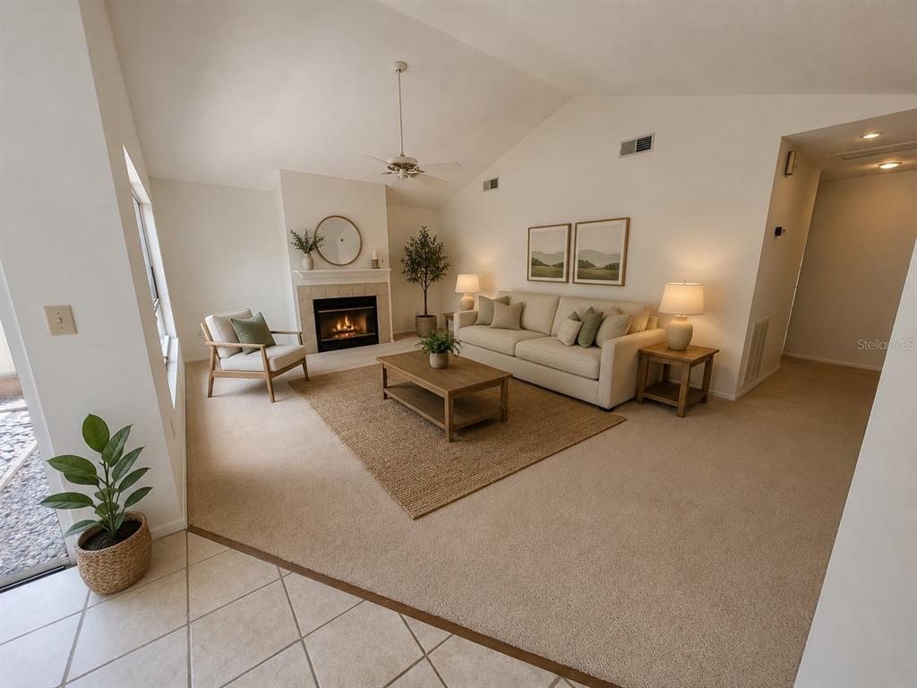 A living room features a fireplace, beige sofa, area rug, and vaulted ceilings — 7125 SILVERMILL DRIVE, TAMPA, FL