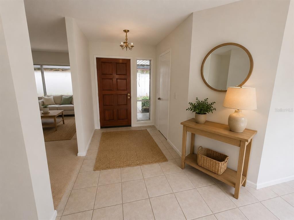 An entryway features a wood front door, tiled floor, console table, and a round wall mirror — 7125 SILVERMILL DRIVE, TAMPA, FL