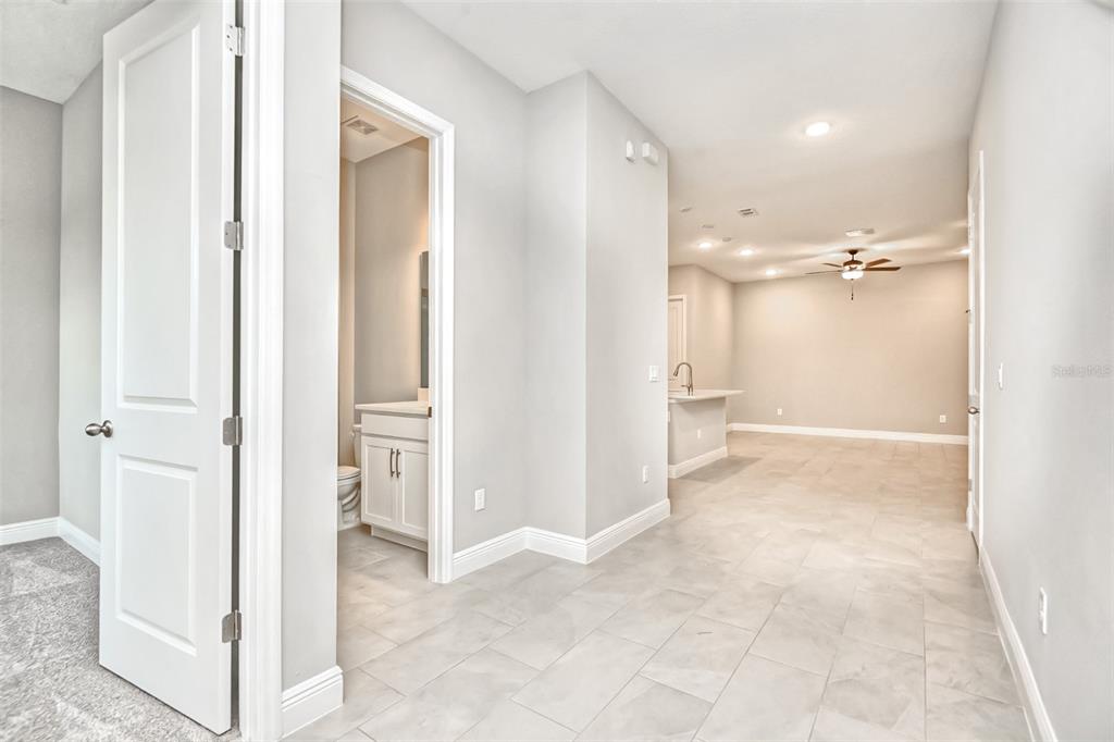 A view from a carpeted room looking into a tiled hallway, bathroom, and open kitchen — 2941 VOYAGER AVENUE, ST CLOUD, FL