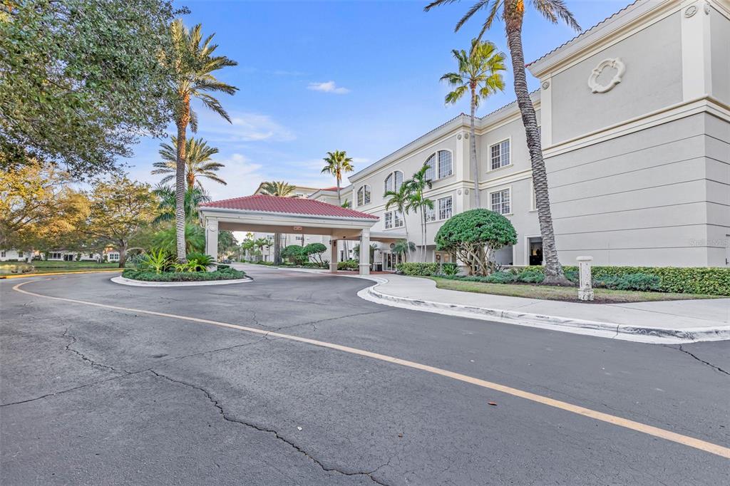 A multi-story building with a covered entrance portico and palm trees in a paved driveway — 3730 CADBURY CIRCLE UNIT 431, VENICE, FL