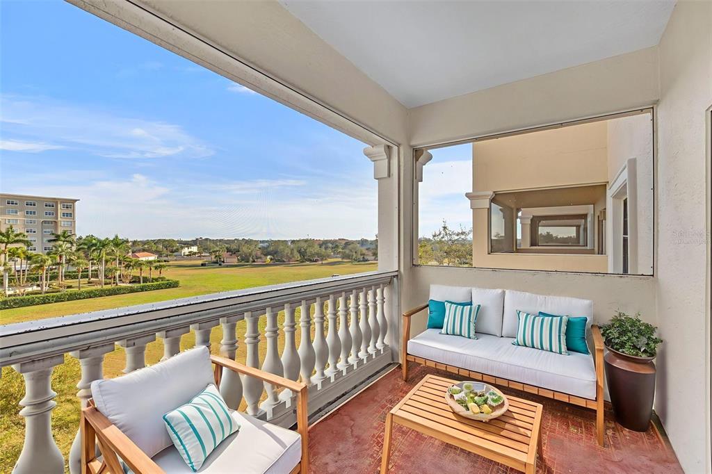 A balcony with a balustrade railing overlooks a grassy field and a distant building — 3730 CADBURY CIRCLE UNIT 431, VENICE, FL