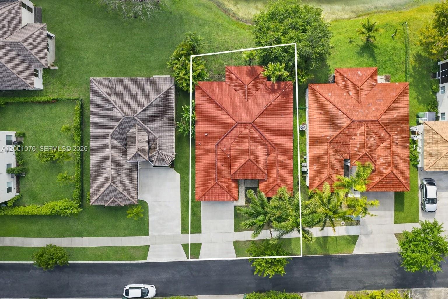 An aerial view shows three suburban houses with tiled roofs and driveways along a street — 690 SE 30th Dr, Homestead FL 33033, HOMESTEAD, FL