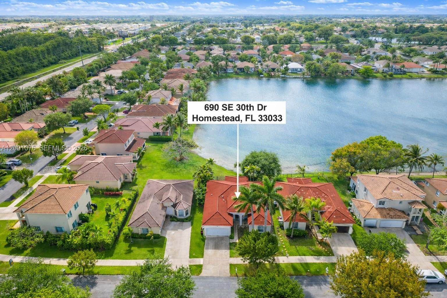 An aerial view shows a residential house with a red tile roof near a lake — 690 SE 30th Dr, Homestead FL 33033, HOMESTEAD, FL