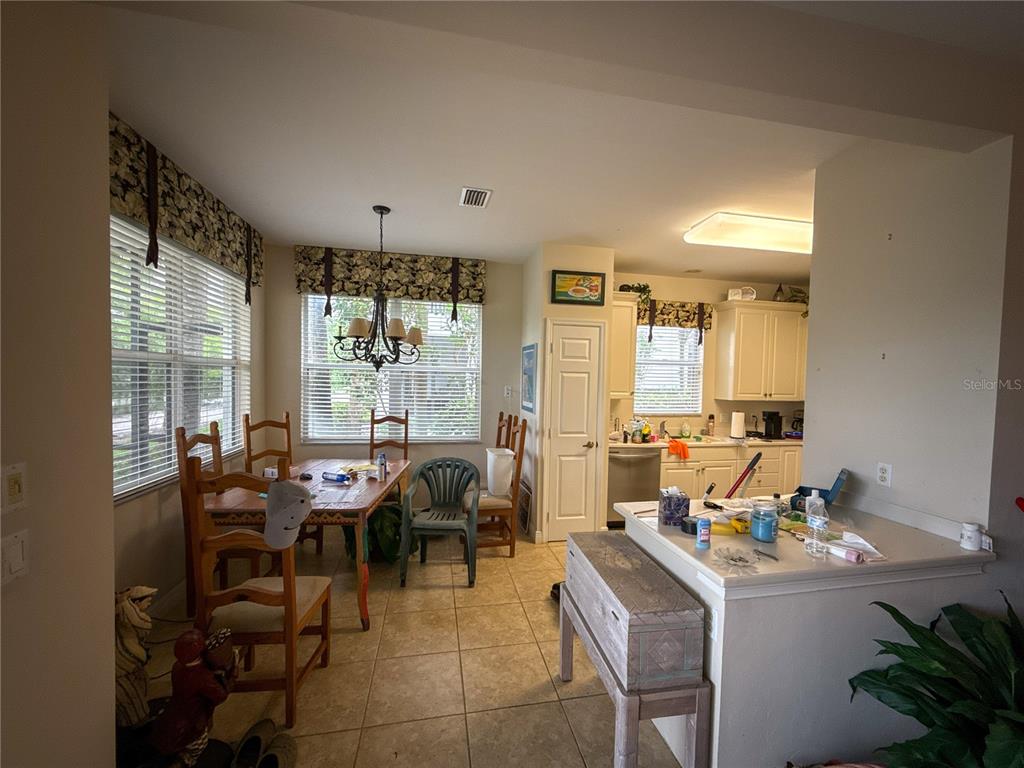 A kitchen and dining area with tile floors, wooden furniture, and a breakfast bar — 12219 TOSCANA WAY UNIT 103, BONITA SPRINGS, FL