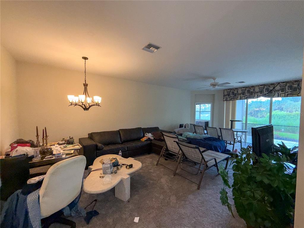 A living room features a dark sectional sofa, a stone coffee table, and a dining area — 12219 TOSCANA WAY UNIT 103, BONITA SPRINGS, FL