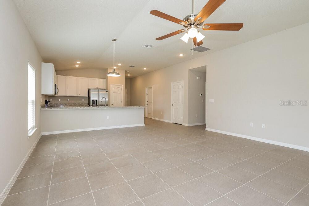 An open-concept kitchen and living area with tile flooring, white cabinetry, and a ceiling fan — 1660 REDFIN DRIVE, POINCIANA, FL
